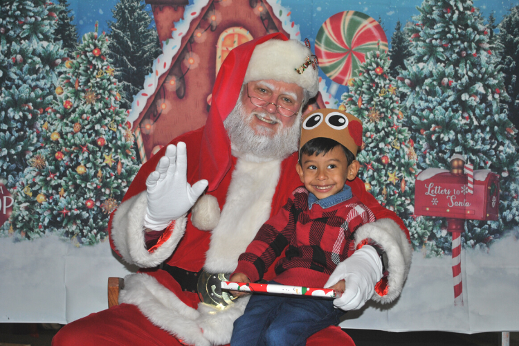 A child smiles as he sits in Santa's lap after receiving a gift. 
