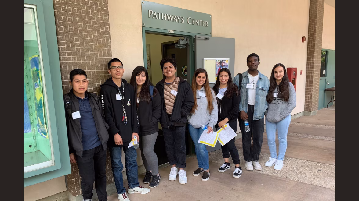 A group of college students stand in a line together in front of a sign that reads Pathways Center