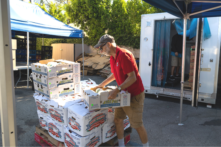A volunteer unloads pallets of produce for a food pantry in Pasadena CA.