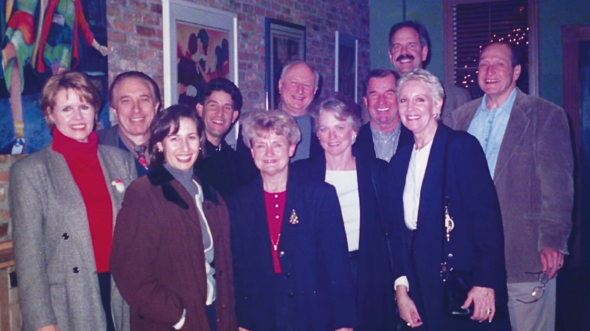 A vintage color photo shows a large group of people in business attire standing together