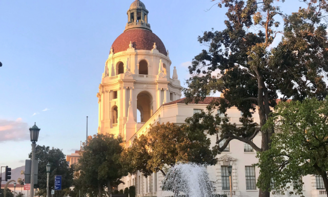 Pasadena City Hall is shown from the side at sunset. The photo is taken looking north and fountain spray is visible in the foreground.