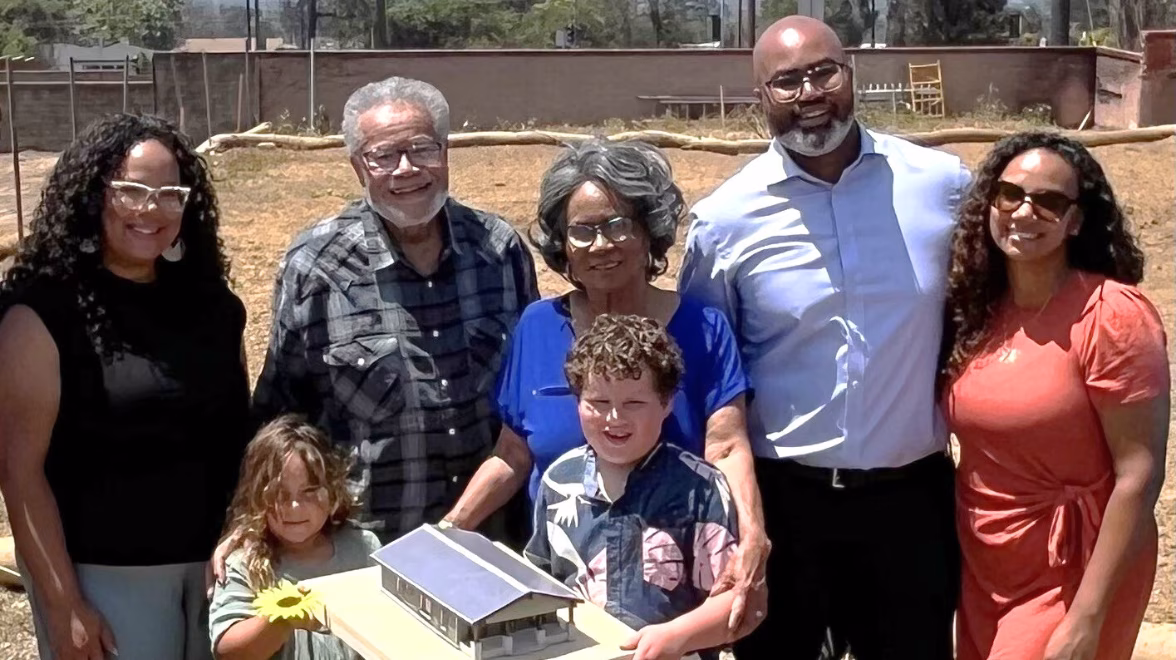 Three generations of an African American family stand on a cleared lot in Altadena following the Eaton Fire