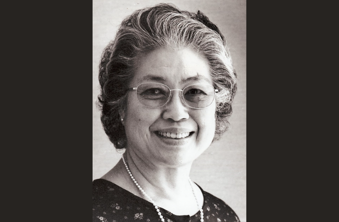 A vintage black and white headshot of an older Asian woman wearing tinted glasses