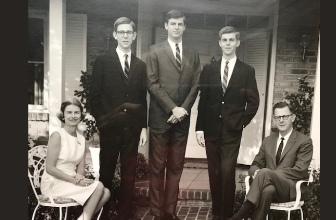 A vintage black and white of a family - 2 parent and 3 young adult men.