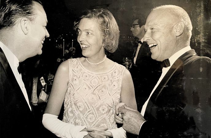 A vinrage black and white photo shows a couple and another man in dress attire laughing together