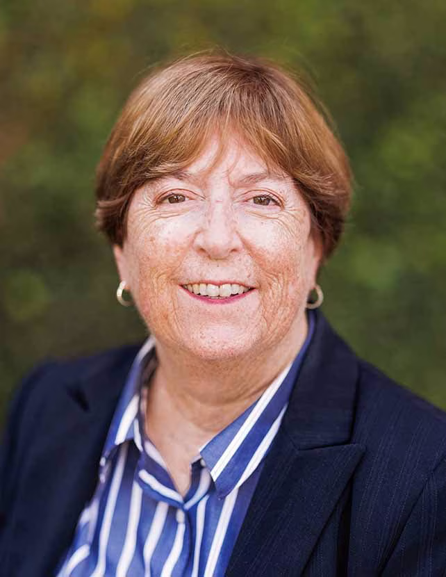 A woman is smiling in a striped blue shirt. Green leaf background.