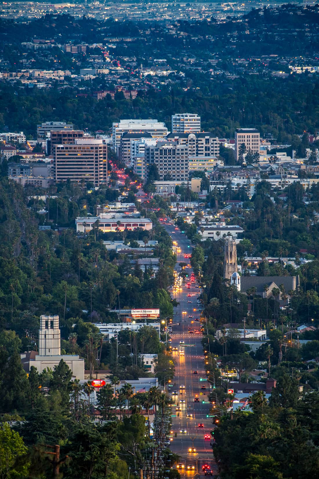 Long shot at dusk of a thoroughfare through a city.