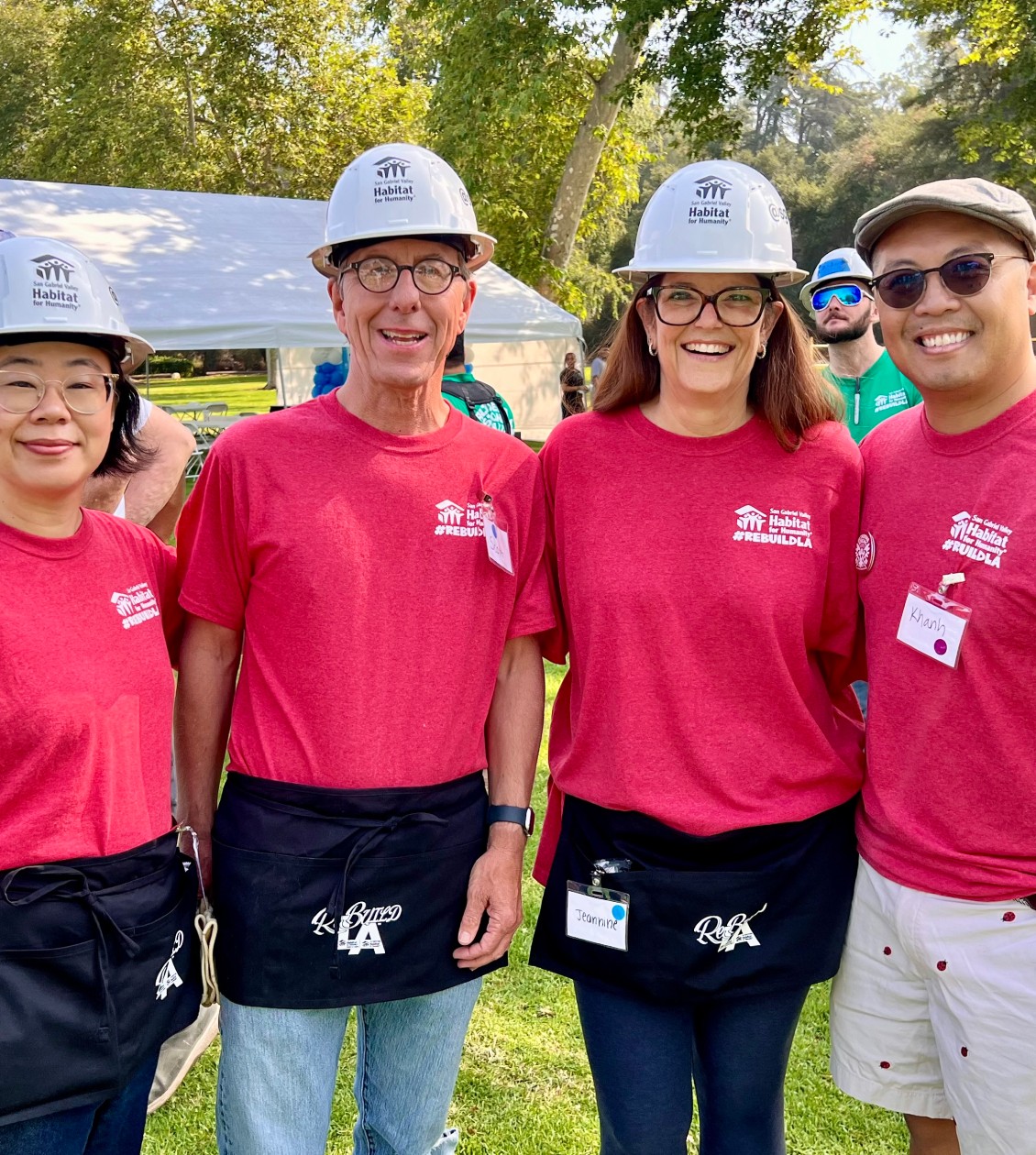 Four habitat for humanity volunteers wearing hardhats and posing for photo
