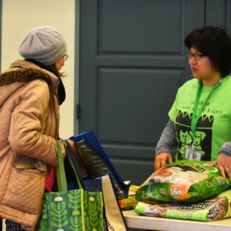 Woman with multiple bags talking to anther person.