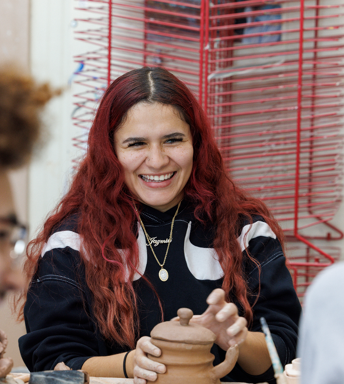 Student smiling in art class holding her clay jar