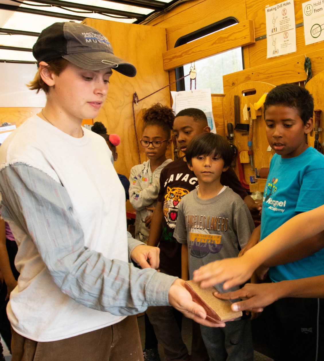 Woman holding block while students touch it