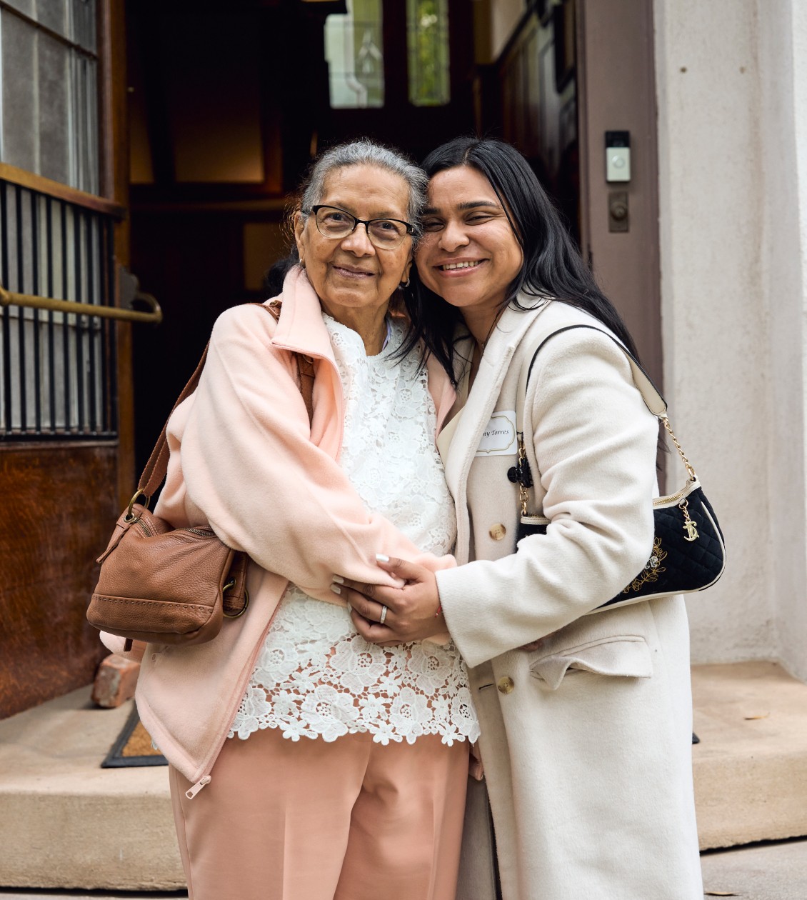 Image of a grandmother and granddaughter posing for a photo in front of steps to a door