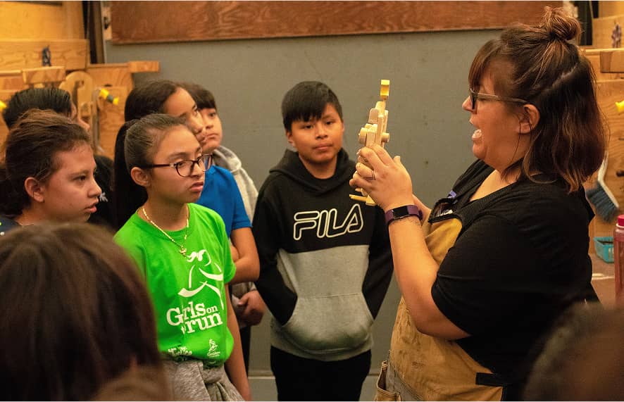 Woman showing item off to a group of students