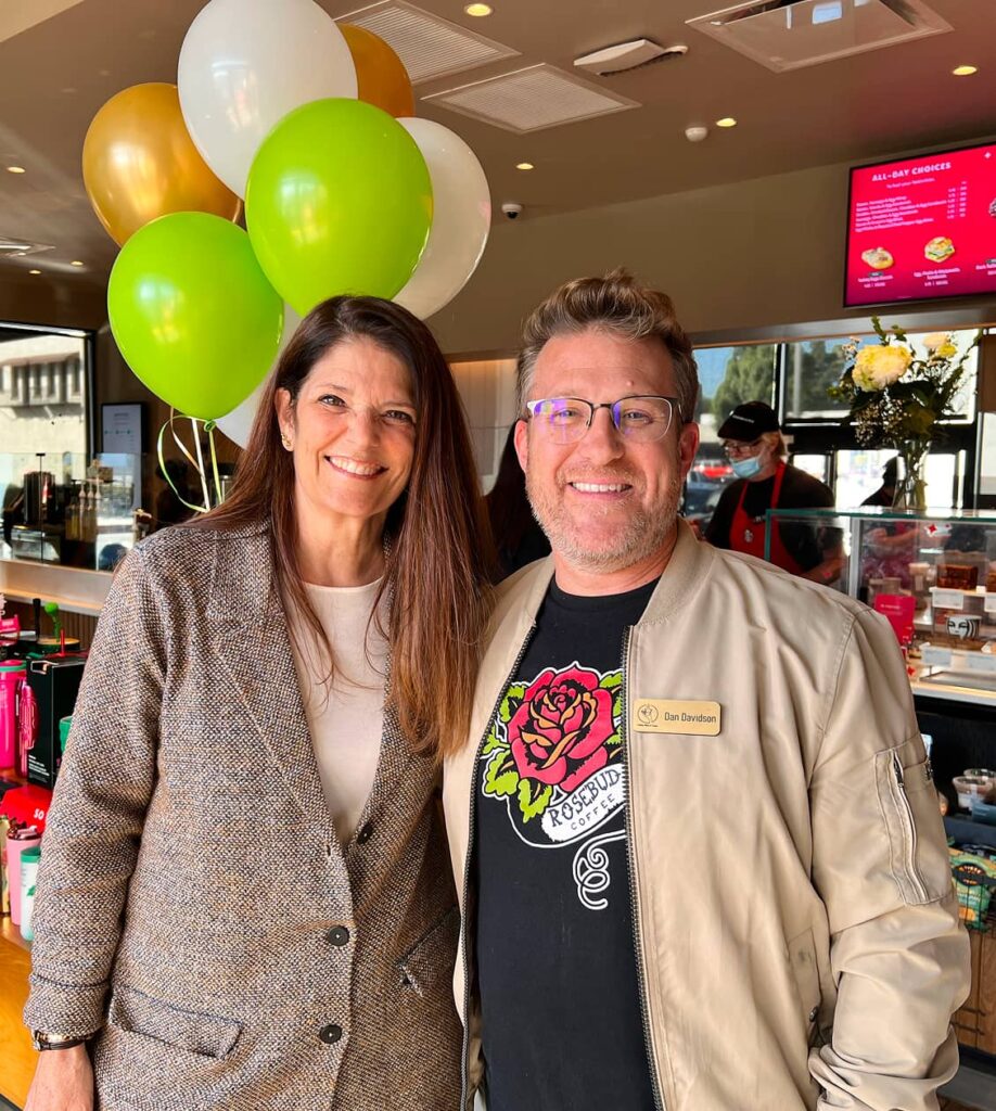 Two people smiling for a photo inside a diner with balloons in the background