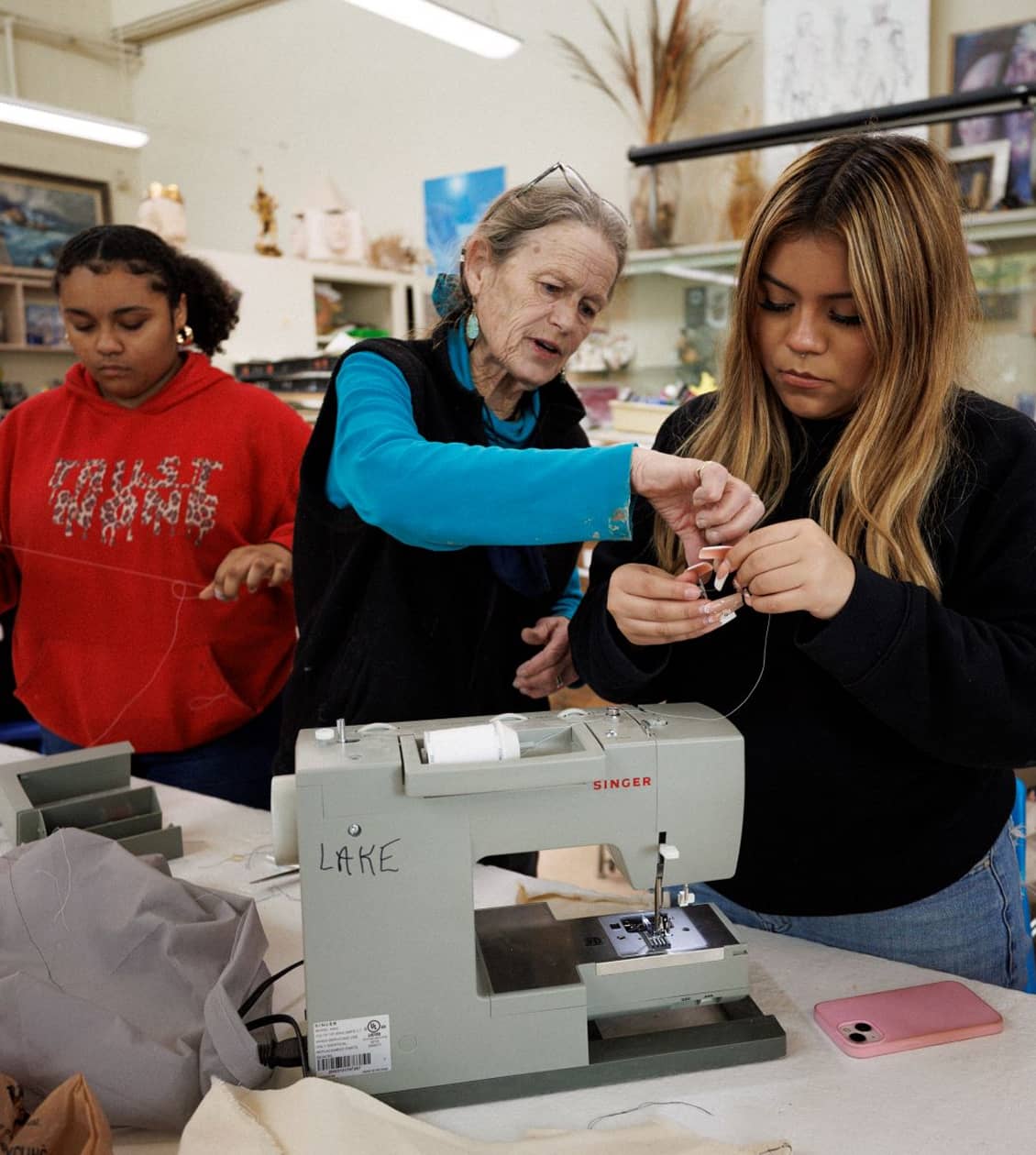 Woman helping student with sewing machine