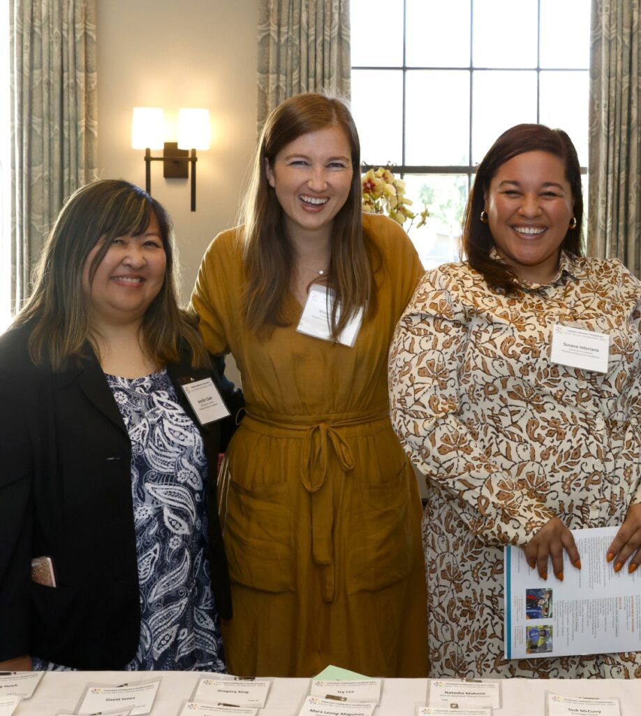 Three women smiling and laughing for a photo with name tags on