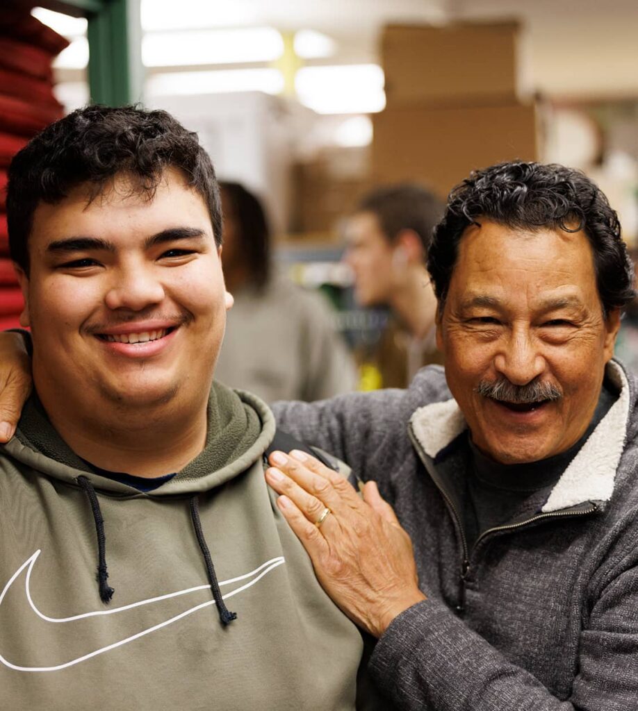 Man patting young adult as they both smile for a photo