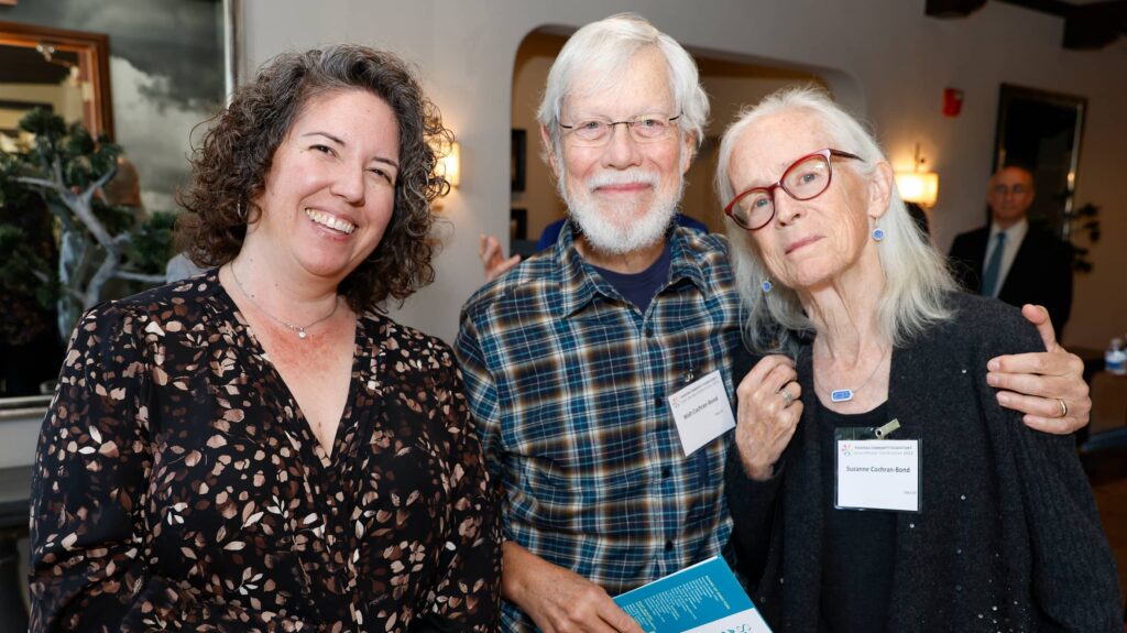 Three people sitting smiling in a photo with name tags on