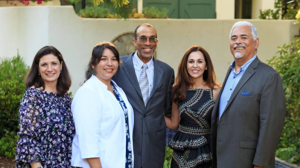 Group of 5 people smiling for a photo outside