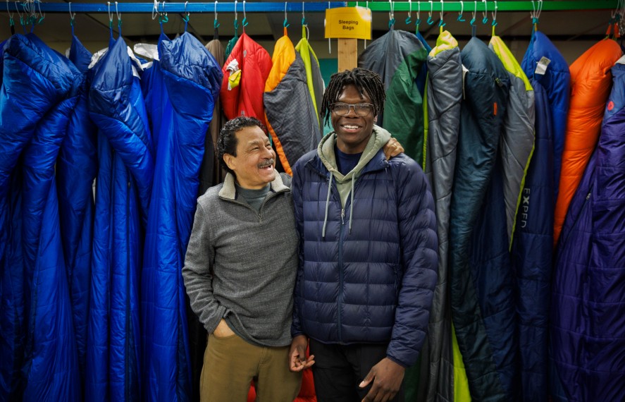 Male student smiling with man infront of hanging gowns