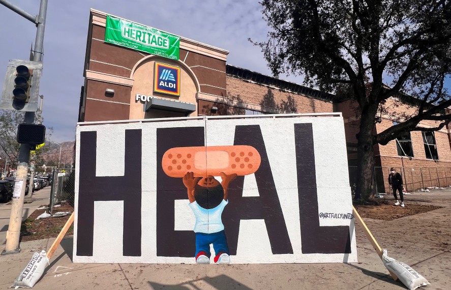 Wall art of young boy putting band-aid on the word heal