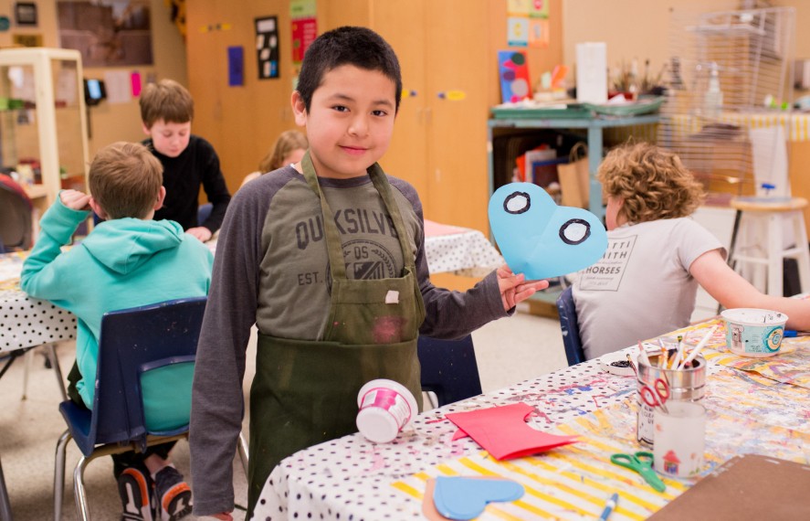 Young boy in art class showing off his creation
