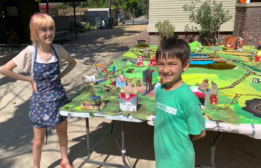 Two kids smiling for a photo in front of a diorama