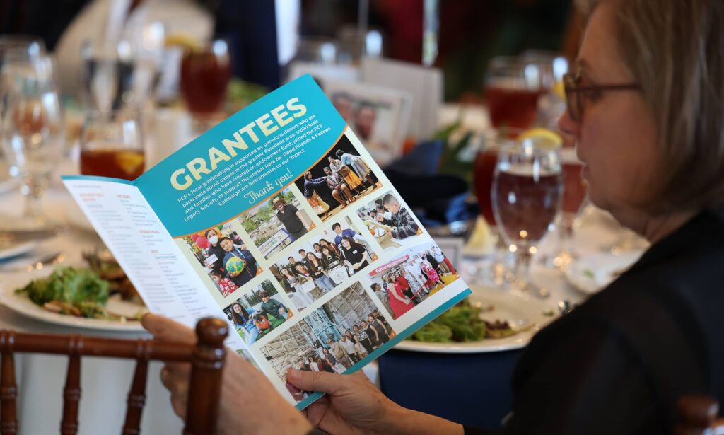 Woman holding a brochure reading page of grantees