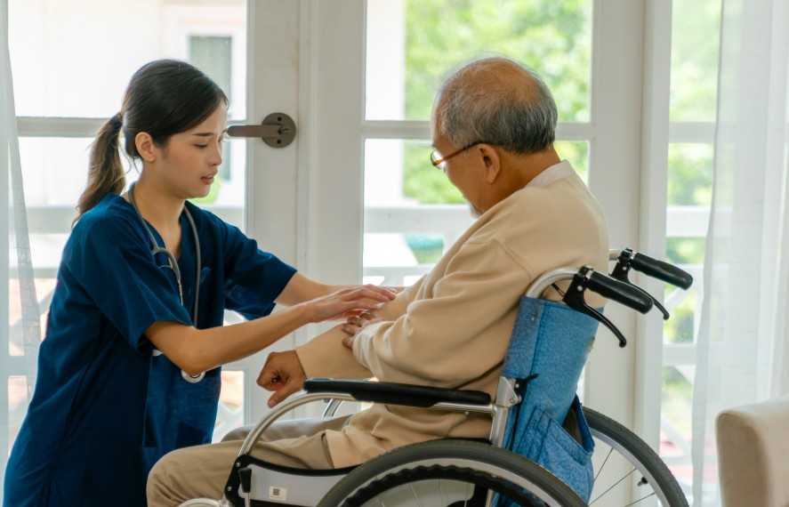 Nurse checking on an edlerly man in a wheelchair