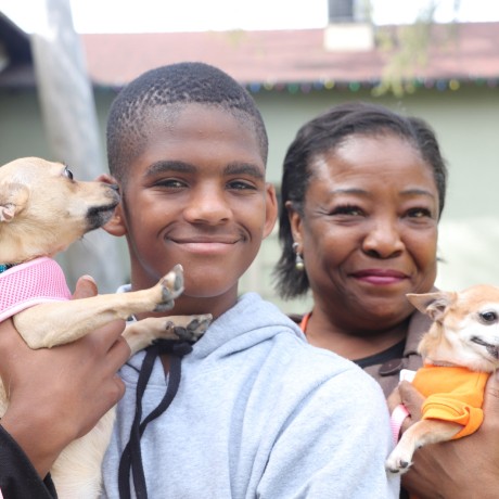 Mom and son smiling and holding their two chihuahuas dogs