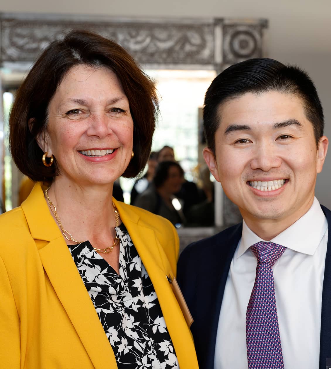 Man and a woman (wearing in yellow blazer) smiling for a photo