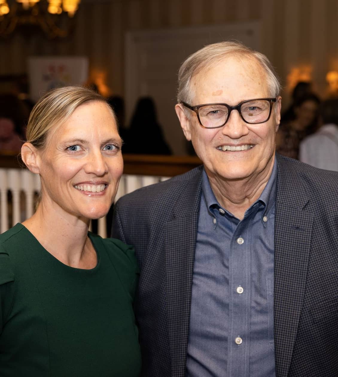 Man and woman (wearing in green) shirt smiling for a photo at an event