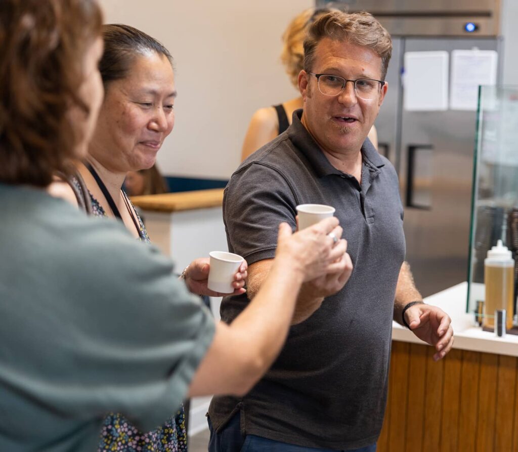 Man handing out small cup to people