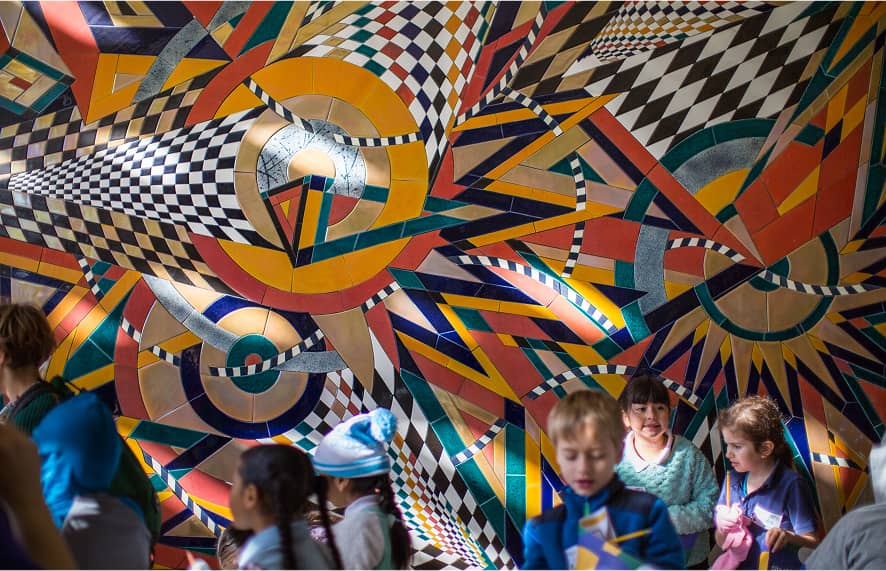 Kids in a room with artistic geometric paterns on wall