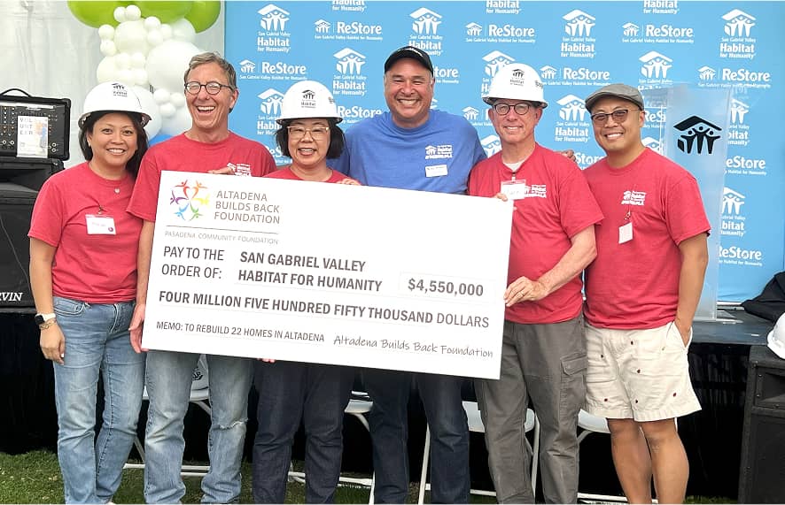 Group of people wearing hard hats accepting a large check