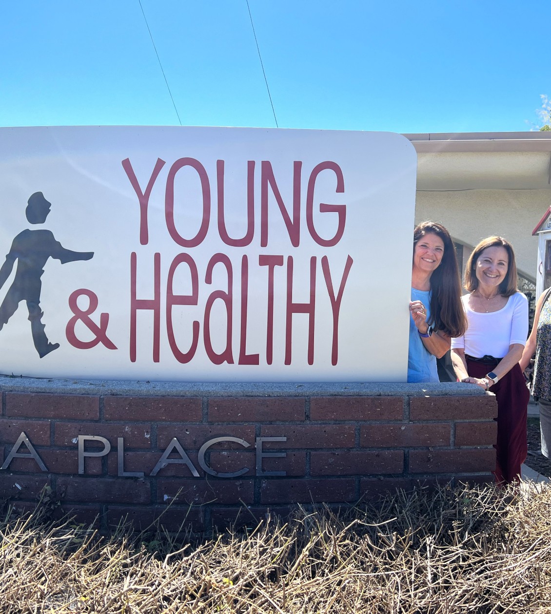 Two Women standing next to Young & Healthy sign
