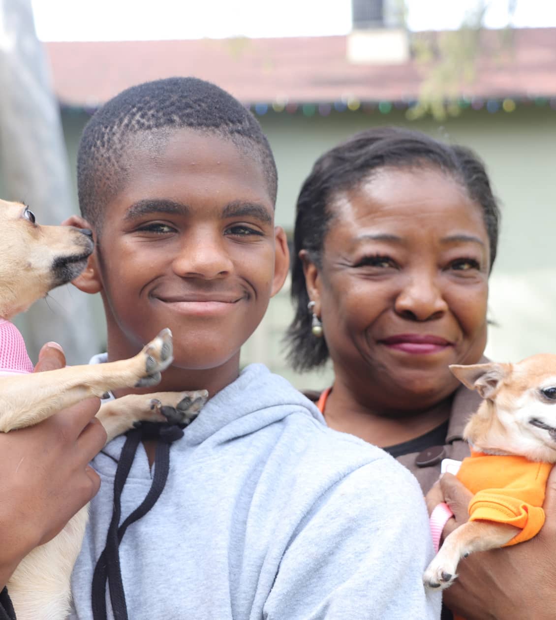 Mom and son smiling and holding their two chihuahuas dogs