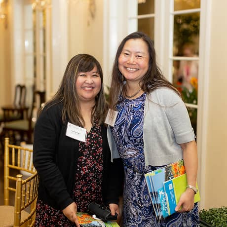 Two people smiling for a photo at an event inside a ballroom
