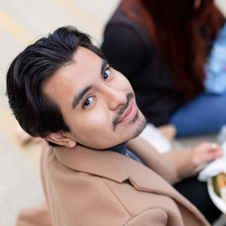 Person looking up at camera with plate full of food in lap