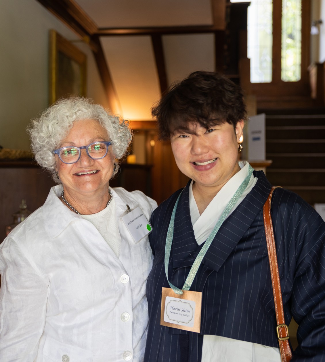 Two women smiling and posing for a photo inside the entrace of a home