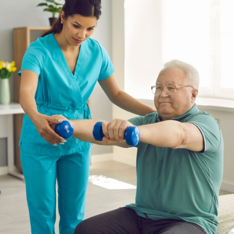 Therapist helping an older gentleman with weights