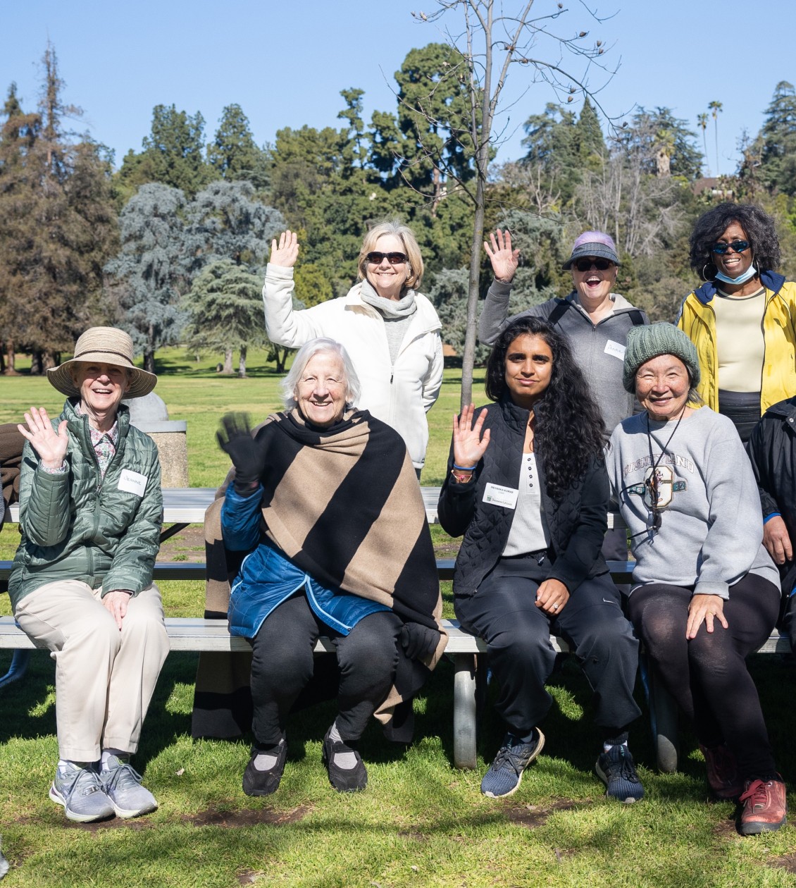 Group of older people smiling and waving in a photo