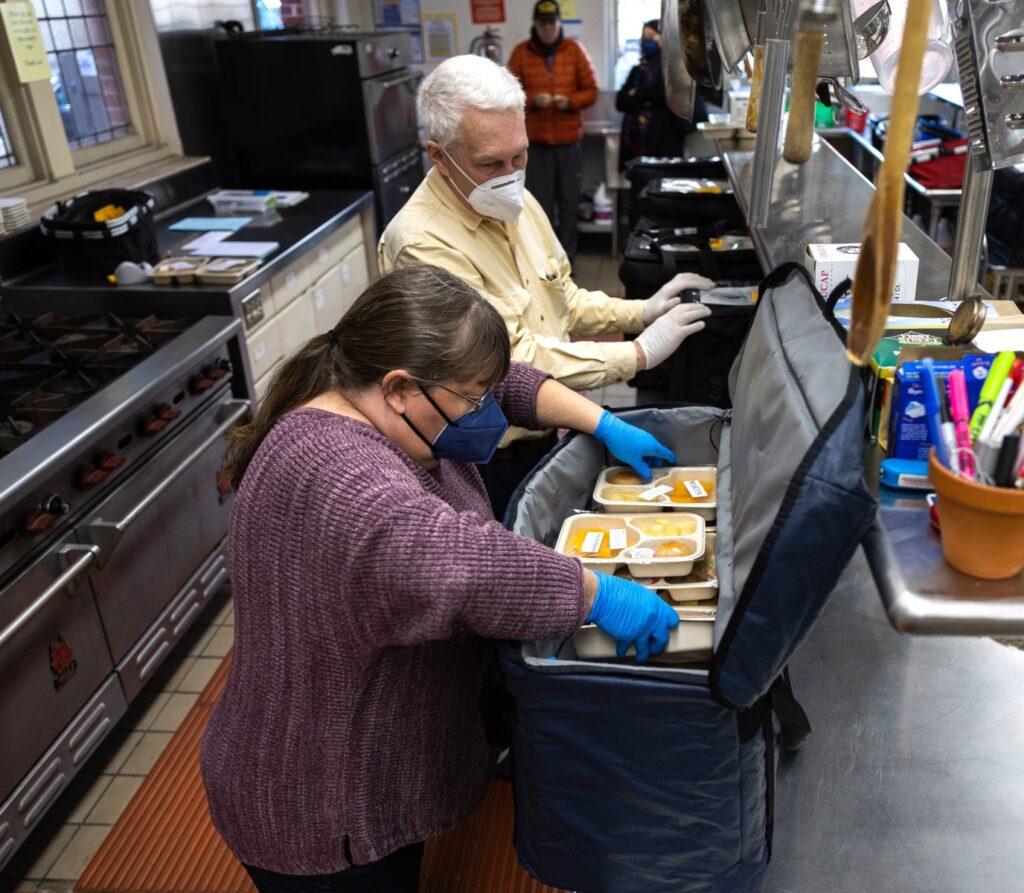 Two people packing meals in a bag