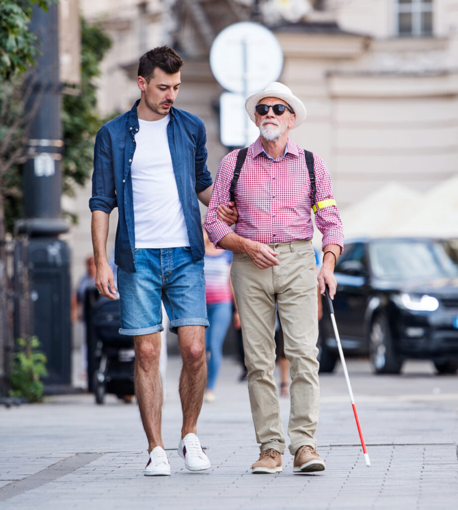 Man guiding a blind man down the street