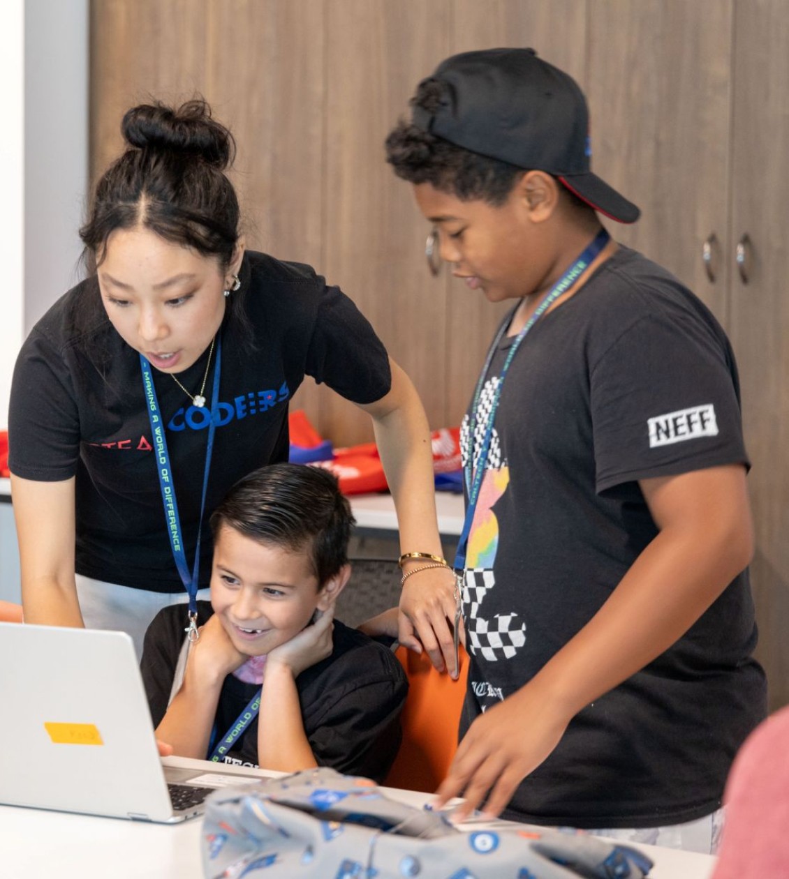 Woman helping two kids on a computer