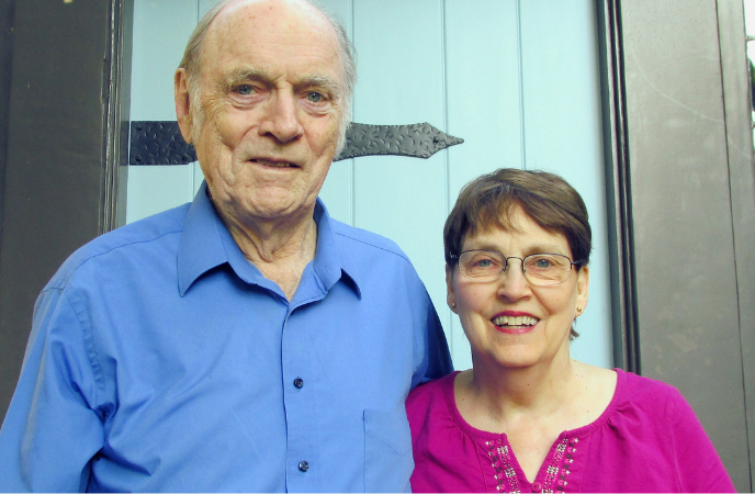 An older couple pose in front of a bright blue door