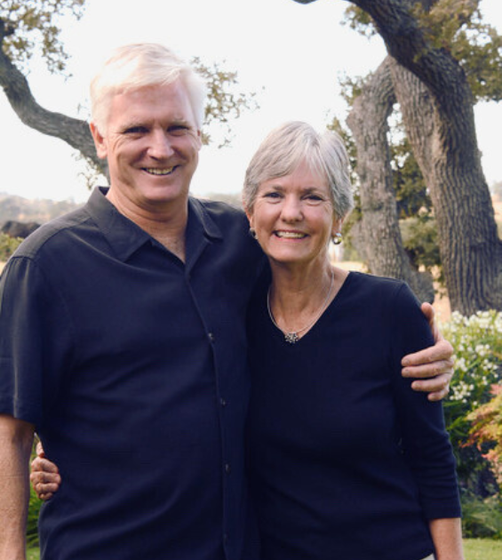 A middle age brother and sister stand together hugging and facing camera