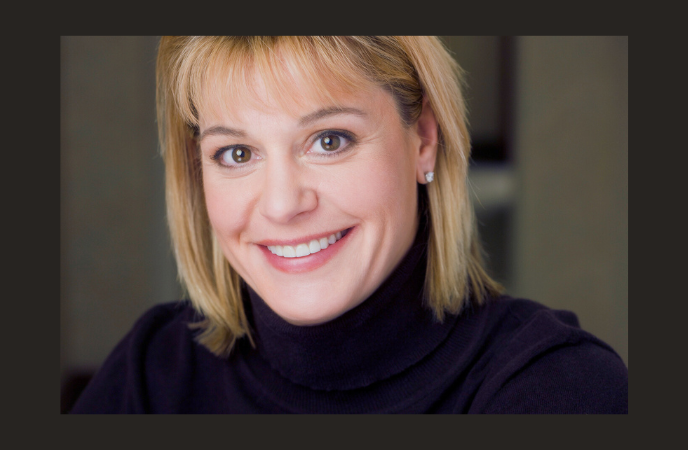 A close-in headshot of a women with blonde hair and wearing a black turtleneck