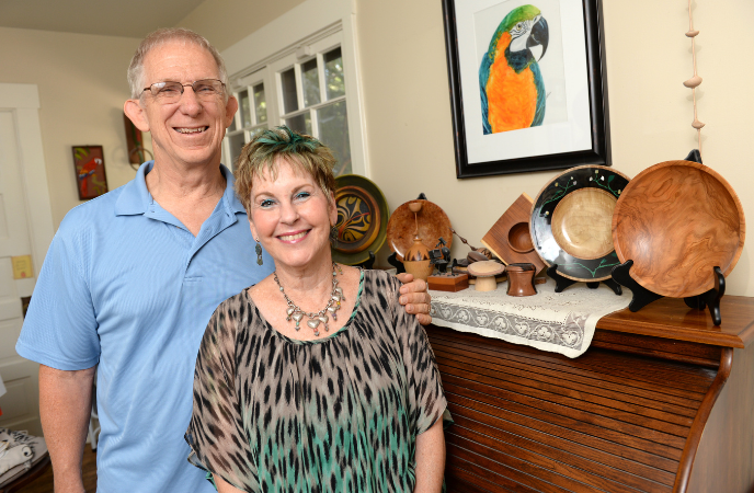 A middle age couple stands indoors by a piano