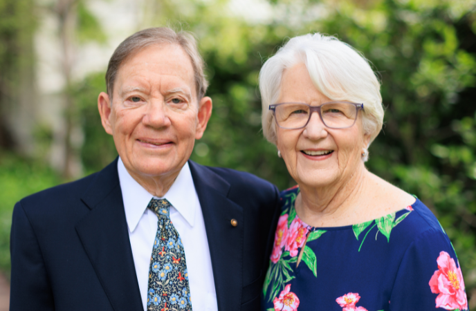 An elderly couple stand together outdoors
